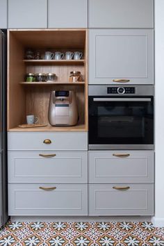 a kitchen with white cabinets and an oven in the center, including a coffee maker