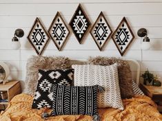 a bed topped with lots of pillows next to a wall mounted art piece on the wall