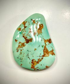 a turquoise stone with gold flecks on it sitting on a white counter top