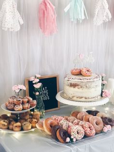 a table topped with lots of donuts next to a cake