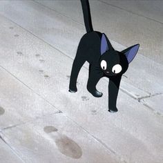 a black cat standing on top of a sidewalk