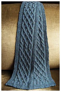 a blue knitted blanket sitting on top of a couch