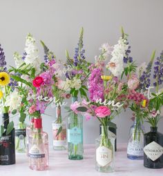 there are many different bottles with flowers in them on the table next to each other