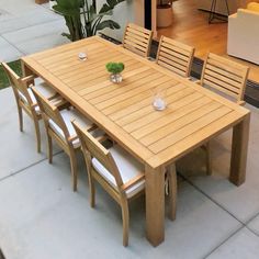 a wooden table with six chairs and a plant on top of it in front of a house