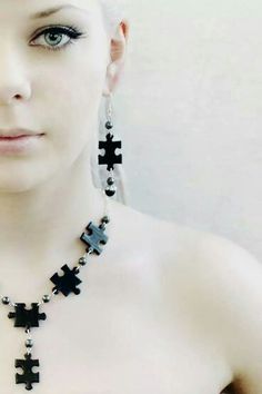 a woman with white hair wearing a necklace made out of black puzzle pieces and beads