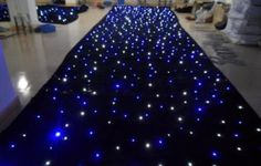 blue and white lights are on the floor in an indoor area with black carpeting