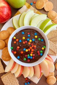 an apple, crackers and chocolate dip on a plate