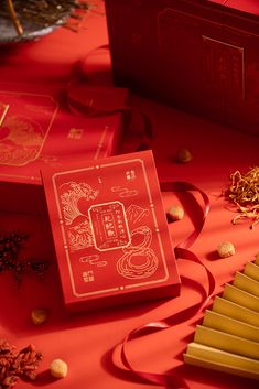 a red box sitting on top of a table next to other boxes and gold decorations