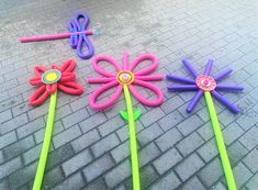 four different colored plastic flowers and scissors on the ground