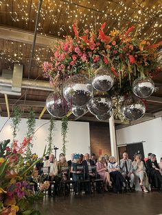 a group of people sitting around tables with disco balls hanging from the ceiling above them