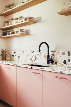 a kitchen with pink cabinets and wooden shelves