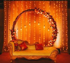 a couch sitting in front of a wall with lights on it and an arch made out of flowers