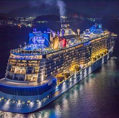 a large cruise ship is lit up at night in the water with lights on it's side