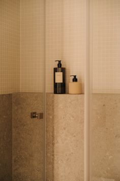 a bathroom with a glass shower door and soap dispenser