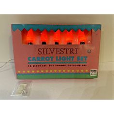 a set of six orange carrot lights in a pink box