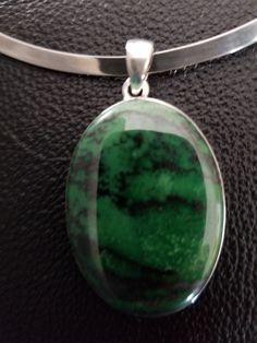 "Large Transvaal Jade stone set in sterling silver pendant. The stone is a dark green with darker stratification. The pendant is 1.5 inches long without the bail; with bail, it measures 1.8 inches. The pendant comes with a sterling silver stiff collar necklace. The necklace is 5.5 inches long and 4.5 inches wide. it has 2.6 inch gap so it can be easily put on or taken off. The collar has a maker's mark and is marked \"925\" and \"Mexico\". The collar can be worn with or without the pendant." Green Polished Sterling Silver Gemstones, Green Pendant Gemstones For Formal Occasions, Green Sterling Silver Gemstones With Polished Finish, Green Cabochon Oval Pendant Necklace, Green Large Pendant Jewelry For Formal Events, Green Oval Necklace With Large Stone, Oval Green Necklace With Large Stone, Formal Green Jewelry With Large Pendant, Green Oval Pendant Jewelry With Large Pendant