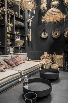 a living room filled with lots of furniture and hanging baskets on the wall above it