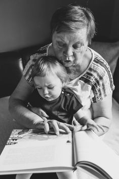 an older woman holding a child while reading a book