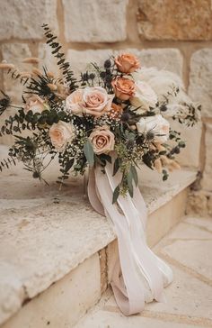 a bridal bouquet sitting on top of a stone ledge next to a brick wall