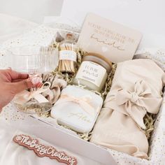 a woman's hand is holding a glass and some items in a gift box