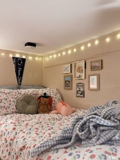 there is a teddy bear laying on the bed in this room with lights strung above it