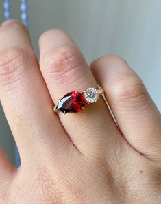 a woman's hand with a diamond and garnet colored ring on her finger