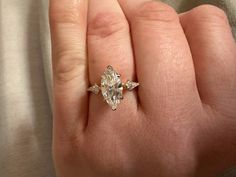 a woman's hand holding an engagement ring with two diamonds on it and the middle one in white gold