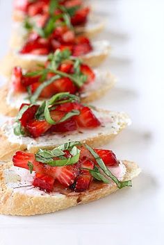 several slices of bread with strawberries and basil on them sitting on a white surface