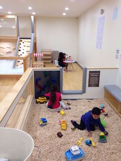 two children playing with toys in a playroom on the floor next to some stairs