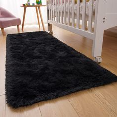 a baby crib with a black rug on the floor