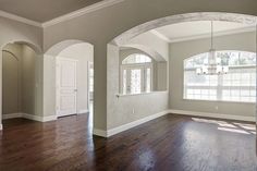 an empty room with hard wood floors and arched windows