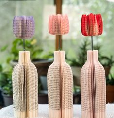 three different colored vases sitting on top of a table next to potted plants