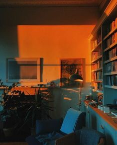 a room with bookshelves and a desk in the middle is lit by sunlight coming through the window