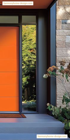 an orange front door on a house with plants in the foreground and trees in the background