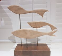 three wooden fish sculptures sitting on top of a wood block in front of a white door