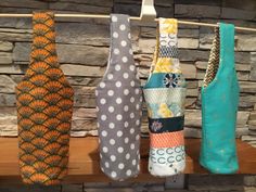 several different colored vases are hanging on a clothes line in front of a stone wall