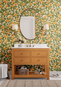 an orange wallpapered bathroom with a round mirror and wooden cabinet underneath the sink