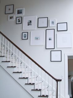 there is a staircase with pictures on the wall and framed photos on the wall above it