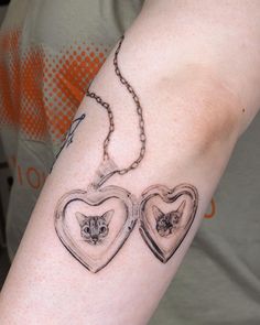 two heart shaped lockes with cats in them on a woman's left arm