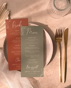 a table setting with silverware and menu cards on it, along with gold cutlery