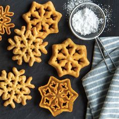 some cookies are sitting on a table next to a bowl and spoon with sugar in it