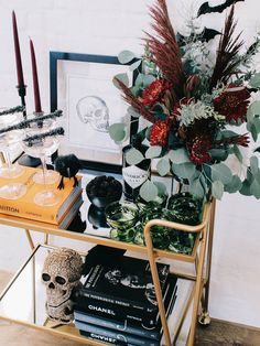 a table topped with books and candles next to a vase filled with flowers on top of a shelf