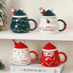 three christmas themed coffee mugs sitting on top of a white shelf next to each other