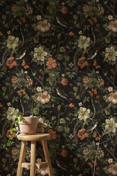 a flowered wallpaper with birds and flowers on it, next to a stool