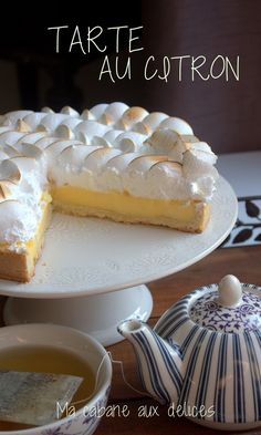 there is a cake on the table with a slice cut out and tea in front of it