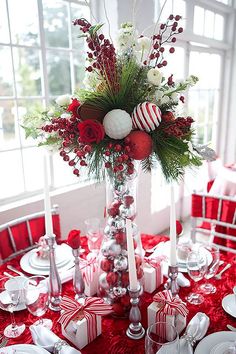 the table is set with red and white dishes, silverware, candy canes, christmas decorations, and candles