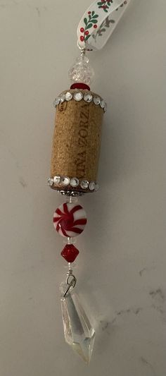 a wine bottle is hanging from a cork and glass bead necklace on a marble surface