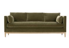 a green velvet couch with two pillows on the back and one arm folded over it