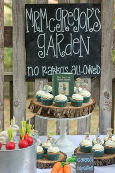 a table topped with cupcakes and carrots next to a chalkboard sign