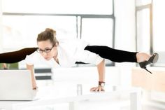 a woman in black pants and white shirt doing a handstand while using a laptop